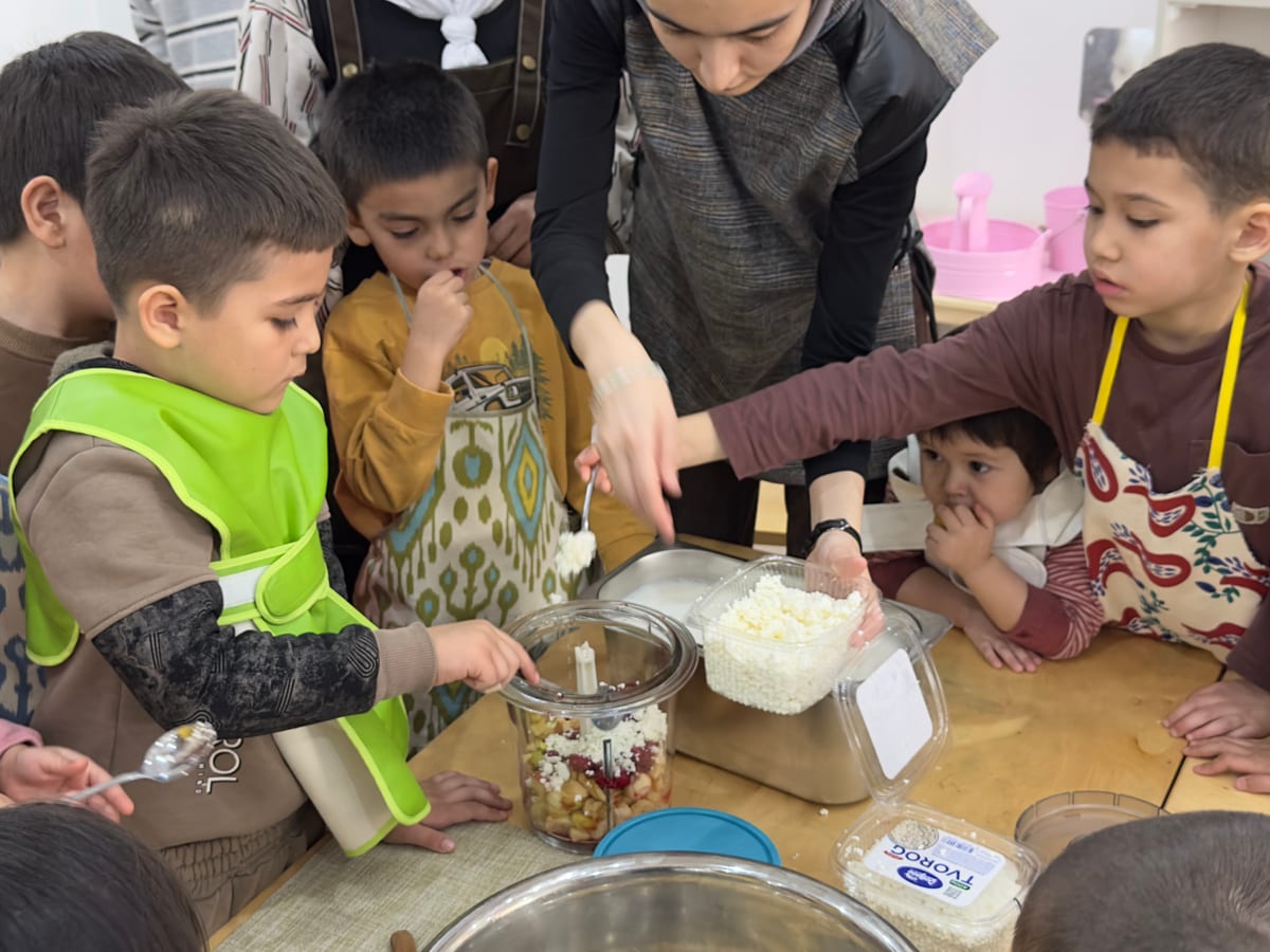 Murabbiy bilan birga ovqat tayyorlayotgan bolalar